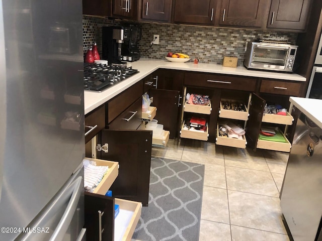 kitchen featuring decorative backsplash, stainless steel fridge, gas cooktop, dark brown cabinetry, and light tile patterned flooring