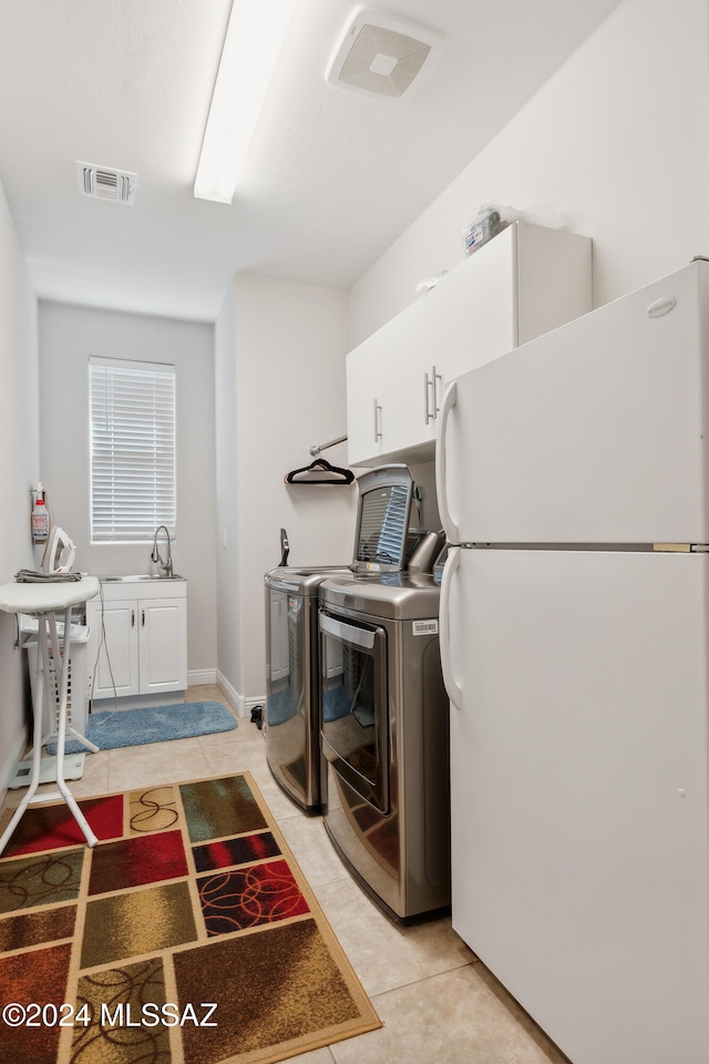 laundry area featuring washer and dryer, cabinets, light tile patterned floors, and sink