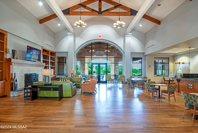 living room with a tiled fireplace, beamed ceiling, high vaulted ceiling, and hardwood / wood-style flooring