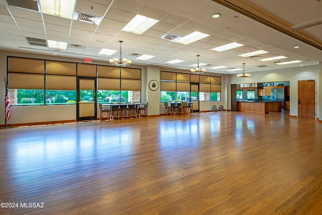 workout area with hardwood / wood-style flooring, a drop ceiling, and a notable chandelier