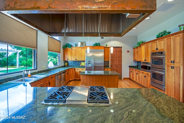 kitchen featuring a center island, dark stone countertops, sink, and appliances with stainless steel finishes