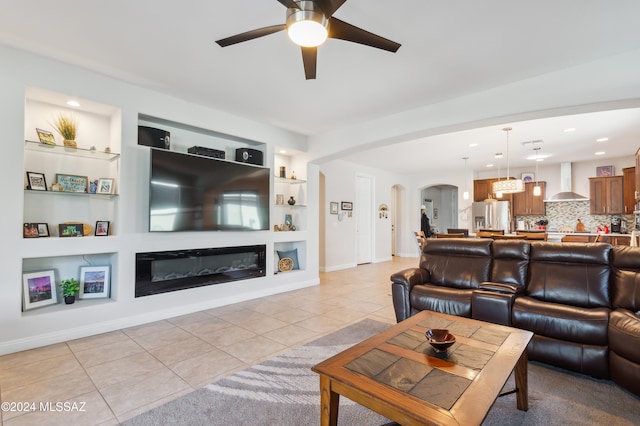 living room with built in shelves, ceiling fan, and light tile patterned flooring