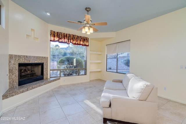 living room with ceiling fan, built in features, a high end fireplace, and light tile patterned floors