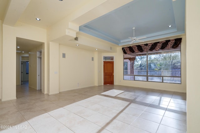 spare room with light tile patterned floors, a tray ceiling, and ceiling fan