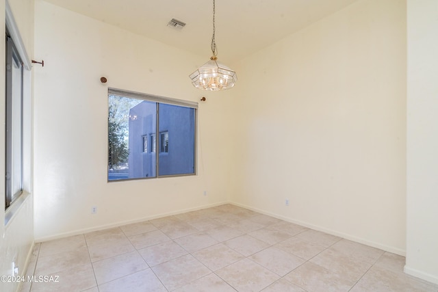 spare room with a chandelier, light tile patterned floors, and vaulted ceiling