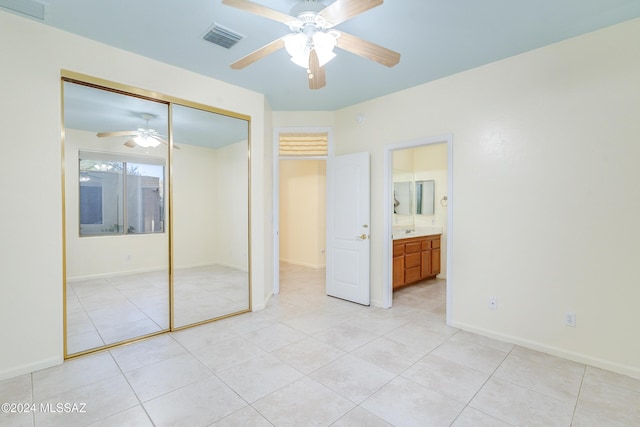 unfurnished bedroom with ensuite bathroom, ceiling fan, sink, a closet, and light tile patterned flooring