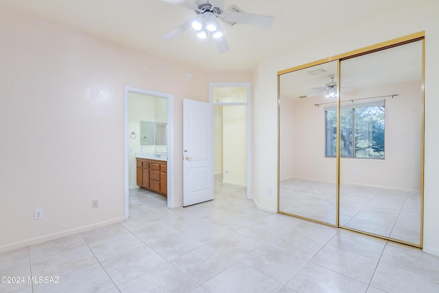 unfurnished bedroom featuring ceiling fan, light tile patterned flooring, ensuite bath, and a closet