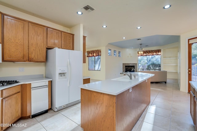 kitchen with a kitchen island with sink, light tile patterned floors, ceiling fan, and white refrigerator with ice dispenser