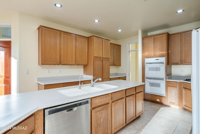 kitchen featuring dishwasher, white double oven, light tile patterned floors, and sink