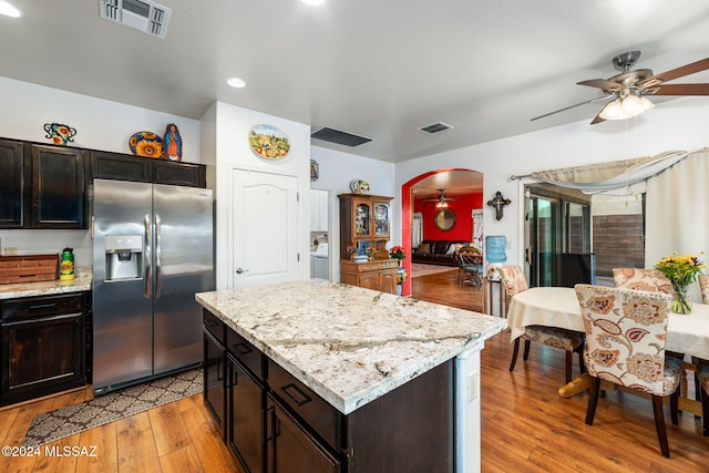 kitchen with ceiling fan, stainless steel fridge, light stone counters, and light hardwood / wood-style flooring