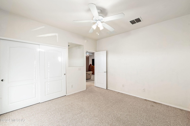 unfurnished bedroom featuring ceiling fan, a closet, and light carpet