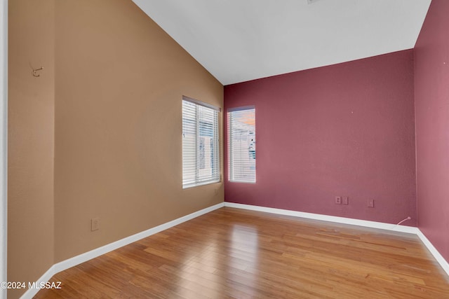 unfurnished room with hardwood / wood-style flooring and vaulted ceiling