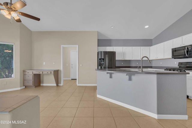 kitchen with lofted ceiling, light tile patterned floors, white cabinetry, sink, and stainless steel appliances