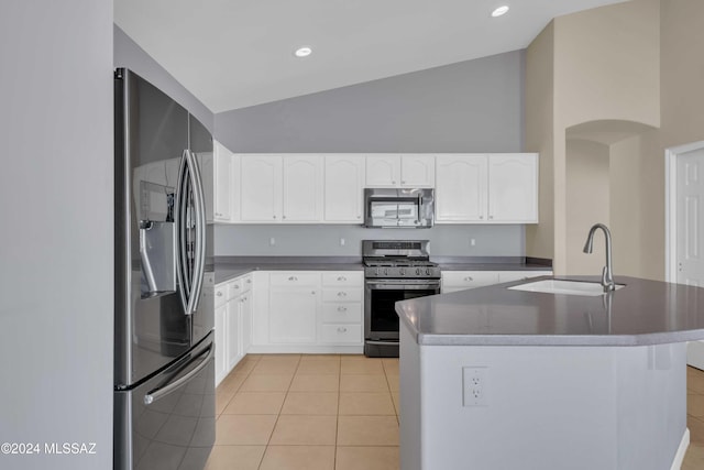 kitchen with an island with sink, sink, white cabinetry, light tile patterned floors, and appliances with stainless steel finishes