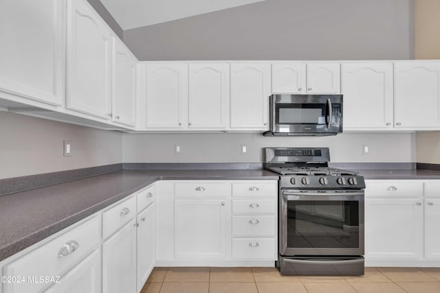 kitchen with light tile patterned floors, stainless steel appliances, lofted ceiling, and white cabinets