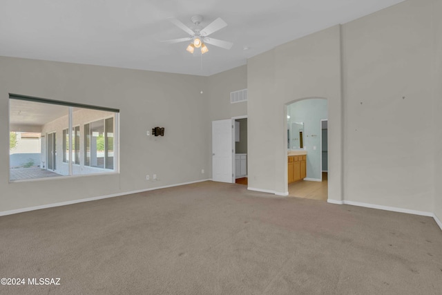 carpeted spare room with a towering ceiling and ceiling fan