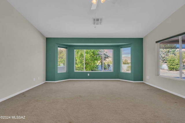 carpeted empty room featuring a wealth of natural light and ceiling fan