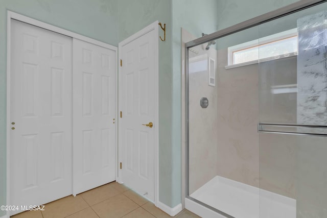 bathroom with a shower with door and tile patterned floors