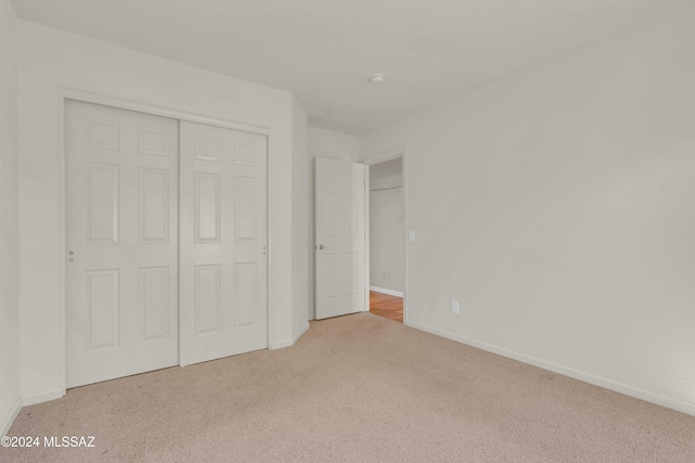 unfurnished bedroom featuring light colored carpet and a closet