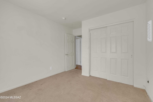 unfurnished bedroom with light carpet and a closet