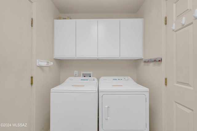 clothes washing area featuring separate washer and dryer and cabinets