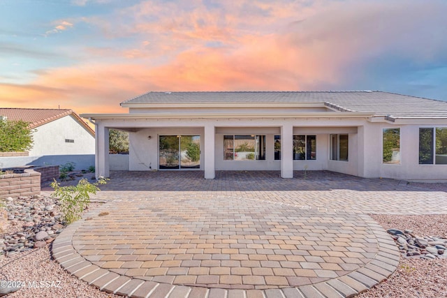 back house at dusk featuring a patio