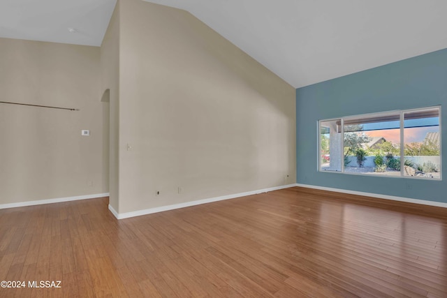 unfurnished living room with hardwood / wood-style floors and high vaulted ceiling