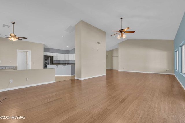 unfurnished living room featuring light hardwood / wood-style flooring, high vaulted ceiling, sink, and ceiling fan