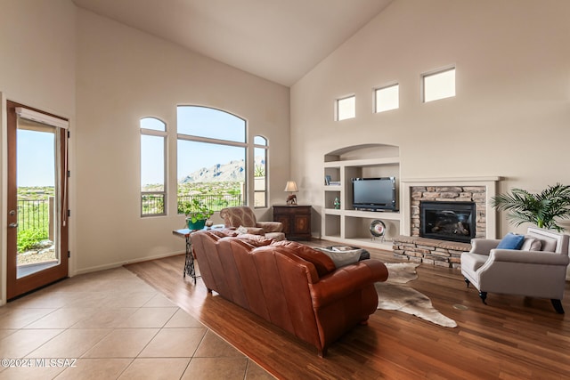 living room with high vaulted ceiling, light tile patterned flooring, a fireplace, and built in shelves