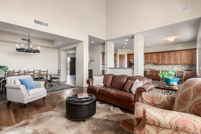 living room with a high ceiling, dark hardwood / wood-style floors, and an inviting chandelier