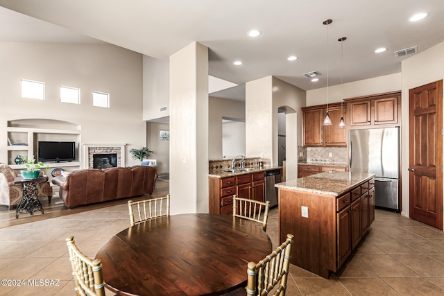 tiled dining room with sink, a stone fireplace, and vaulted ceiling