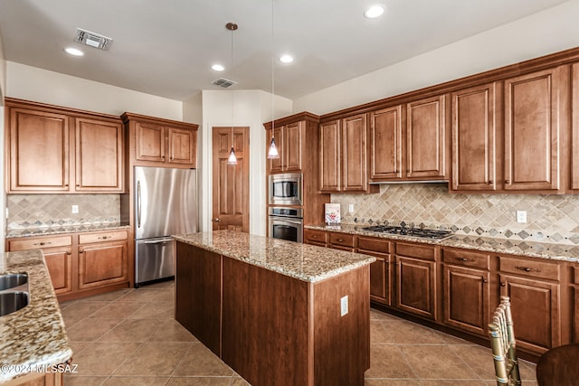 kitchen with light stone countertops, a kitchen island, backsplash, decorative light fixtures, and built in appliances