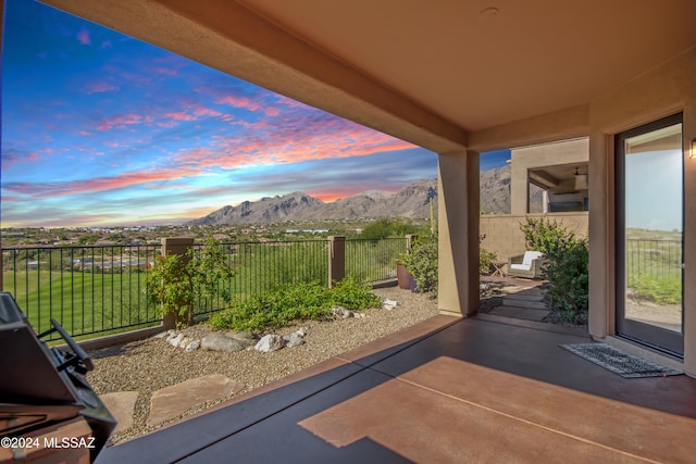 patio terrace at dusk featuring a mountain view and a lawn