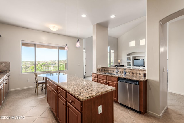 kitchen featuring a kitchen island, lofted ceiling, decorative light fixtures, stainless steel dishwasher, and light stone counters