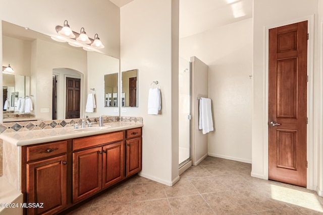 bathroom with a shower with door, vanity, and tile patterned flooring