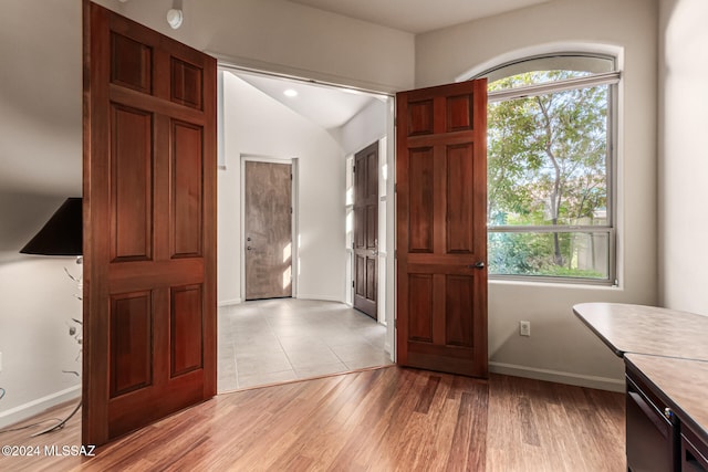 foyer entrance with vaulted ceiling and light hardwood / wood-style flooring