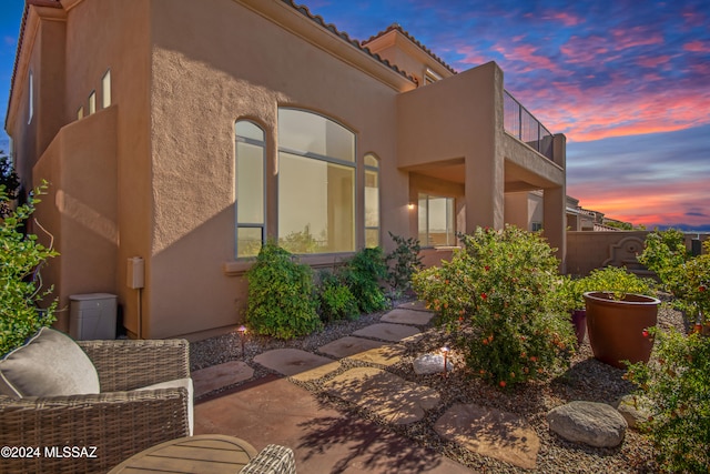 property exterior at dusk featuring a patio