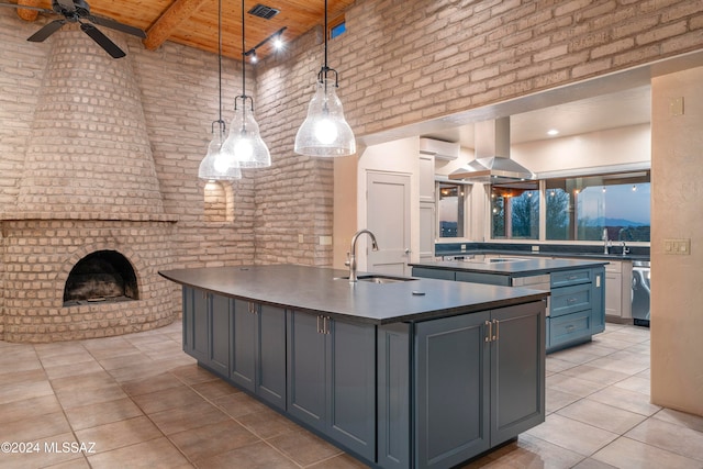 kitchen with wood ceiling, an island with sink, sink, a towering ceiling, and decorative light fixtures