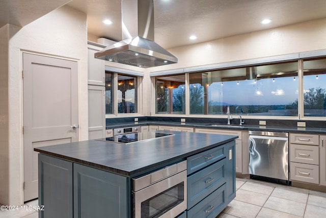 kitchen featuring appliances with stainless steel finishes, island range hood, light tile patterned flooring, sink, and a center island