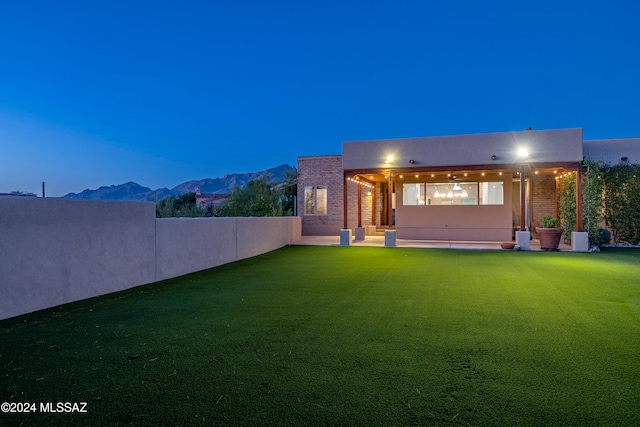 back house at dusk with a yard and a mountain view