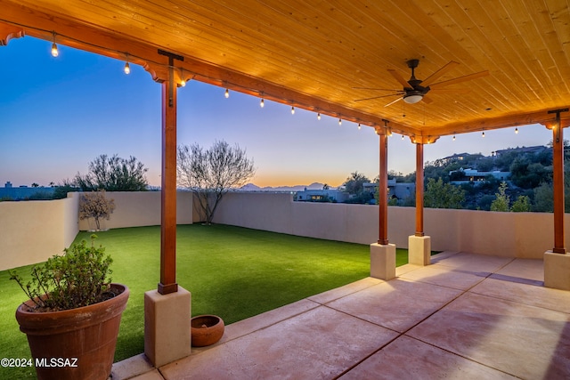 patio terrace at dusk with a yard and ceiling fan