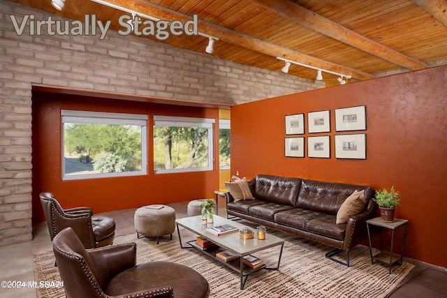 living room with beamed ceiling, wood ceiling, track lighting, and brick wall