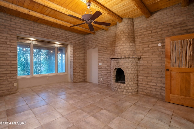 unfurnished living room with a fireplace, ceiling fan, wooden ceiling, beam ceiling, and brick wall