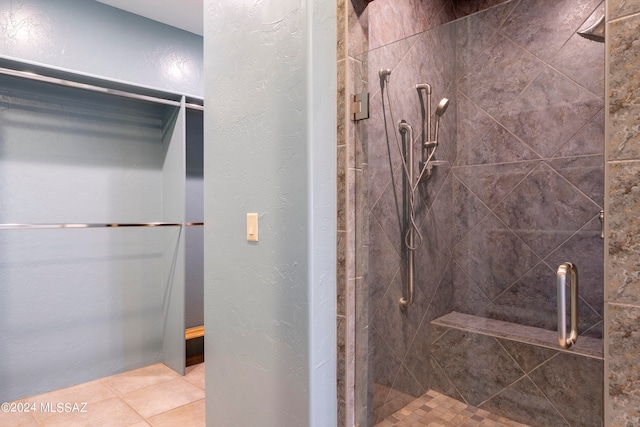 bathroom with a shower with door and tile patterned floors