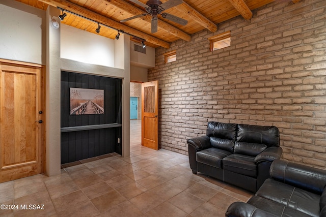 tiled living room with brick wall, beam ceiling, wooden ceiling, and ceiling fan