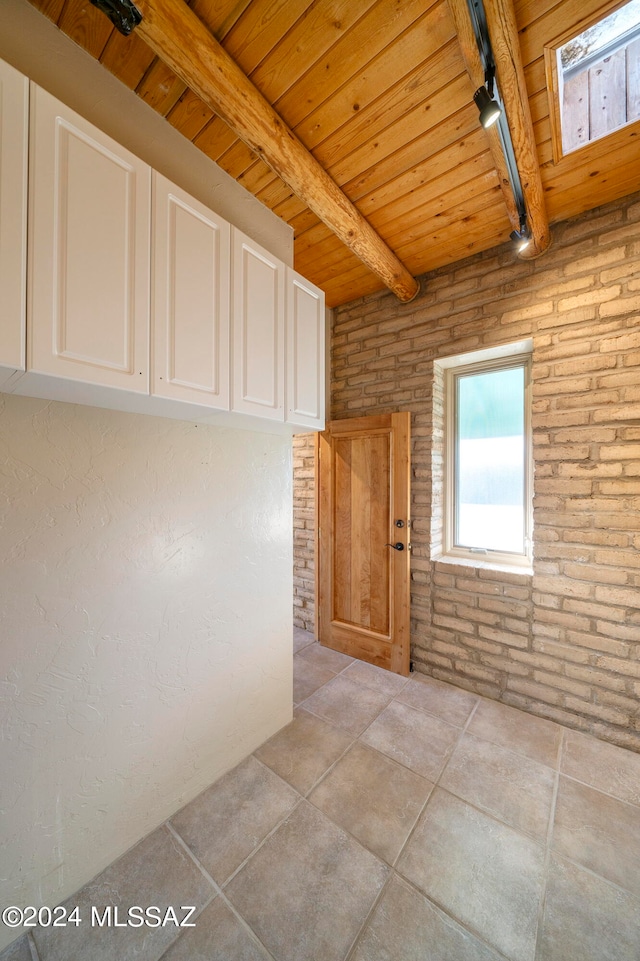 spare room featuring brick wall, beam ceiling, wooden ceiling, and a skylight