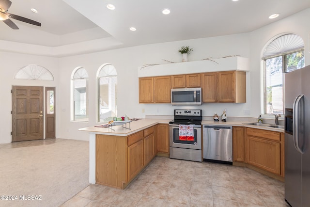 kitchen with stainless steel appliances, light carpet, sink, kitchen peninsula, and ceiling fan