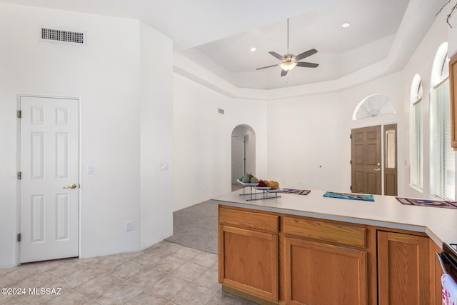 kitchen with light tile patterned flooring, ceiling fan, and a raised ceiling