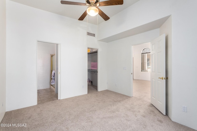 unfurnished bedroom with ensuite bathroom, light colored carpet, ceiling fan, and a closet