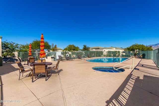 view of swimming pool featuring a hot tub and a patio area